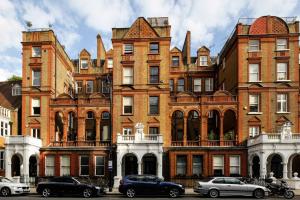 Exclusive Apartments South Kensington في لندن: مبنى كبير من الطوب فيه سيارات متوقفة أمامه