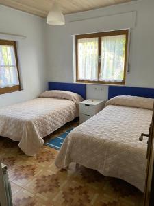 1 dormitorio con 2 camas y 2 ventanas en Casa Tali, en Llanes