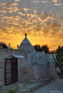 an old stone building with a sunset in the background at Dimore Storiche - Ulivo di Aldo in Martina Franca