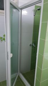 a glass shower in a bathroom with green tiles at Apartament 13 Central in Târgu-Mureş