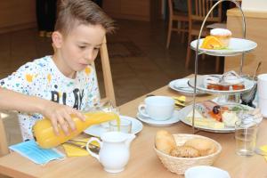 Ein kleiner Junge sitzt an einem Tisch und bereitet Essen vor. in der Unterkunft Gästehaus Zehmerhof bei Erding in Walpertskirchen