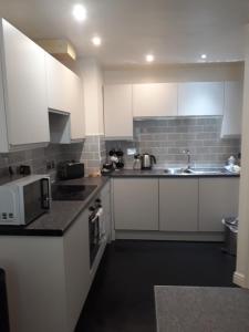 a kitchen with white cabinets and a sink and a microwave at Victoria Bar Apartments Within the City Walls Free Parking in York