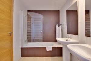Baño blanco con bañera y lavamanos en The Residences At Mar Menor Golf & Resort, en Torre-Pacheco
