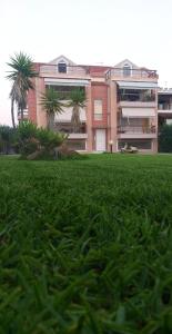 a building with palm trees in front of a field of grass at Ostria Seaside Apartments in Patra