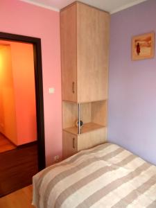 ミエンジボジェにあるSonatka w Apartamentowcu Sonataのピンクと紫の壁のベッド1台が備わるベッドルーム1室