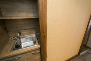a sink in a small room with a wooden cabinet at Sunrise Village Hotel Apartments in Skopelos Town