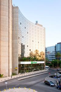 un gran edificio con coches estacionados frente a él en Holiday Inn Lisbon-Continental, an IHG Hotel, en Lisboa