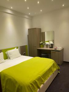 a hotel room with a large bed with a yellow blanket at Parliament Square in Bucharest