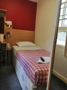 1 dormitorio con 1 cama con mando a distancia en Colliers Hotel, en Londres