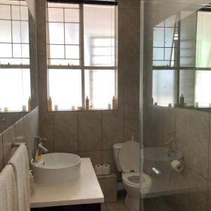 baño con lavabo, aseo y ventanas en Sandton Luxury Living at 102 Kambula, en Johannesburgo
