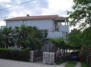 a white house with a fence in front of it at Apartmani Elena in Malinska