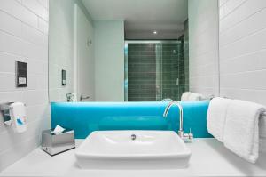 a white and blue bathroom with a sink and a shower at Holiday Inn Express Amsterdam - North Riverside by IHG in Amsterdam