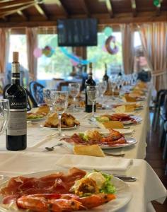 - une longue table avec des assiettes de nourriture et une bouteille de vin dans l'établissement Posada Camino de Altamira, à Santillana del Mar