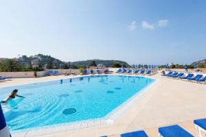 una mujer nadando en una piscina con sillas azules en La Petite Cachette - Pool and 150m to the beach, en Villefranche-sur-Mer