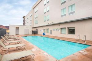 a swimming pool with lounge chairs and a building at La Quinta by Wyndham Kanab in Kanab