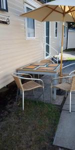 a table with two chairs and an umbrella at Haven Rockley Park,Lytchett Bay View in Hamworthy