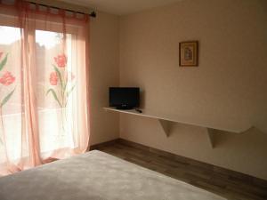 a bedroom with a bed and a window with a television at Auberge Pen Mur in Muzillac