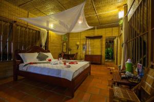 a bedroom with a bed with red flowers on it at Mekong Ecolodge Bungalow in Cai Be