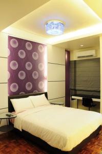 a bedroom with a white bed and a purple wall at The One Vacation Home in Malacca