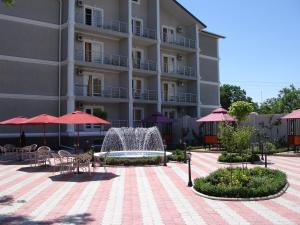 a building with tables and umbrellas and a fountain at Отель Анна Мария in Kurortne