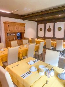 uma sala de jantar com mesas amarelas e cadeiras brancas em Hotel Adonis em Zermatt