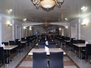 a dining room with tables and chairs and a chandelier at Отель Анна Мария in Kurortne