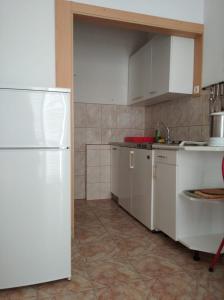 cocina con armarios blancos y nevera blanca en Apartments Atlantida, en Marina