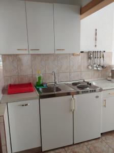 una cocina con armarios blancos y fregadero en Apartments Atlantida, en Marina