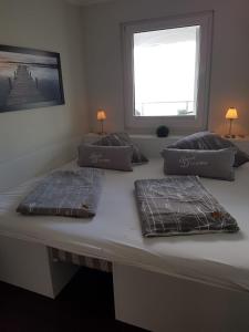 a bed with three pillows on it with a window at Meerblickappartement in Glücksburg