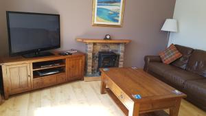 ein Wohnzimmer mit einem TV und einem Kamin in der Unterkunft The Curling Pond, Dalmally Road, Inveraray in Inveraray
