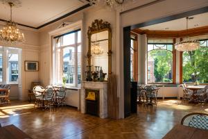 een woonkamer met een open haard en tafels en stoelen bij Boutique hotel Shamon in Eeklo