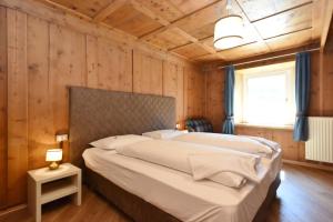 a bedroom with a large bed in a wooden wall at Casa Dorich in Pozza di Fassa