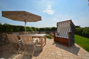 een tafel en stoelen met een parasol en een televisie bij Deichstieg in Westerland