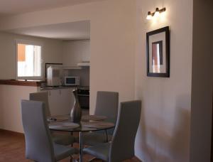una sala da pranzo con tavolo e sedie e una cucina di Apartamento Buganvillea ad Alaior