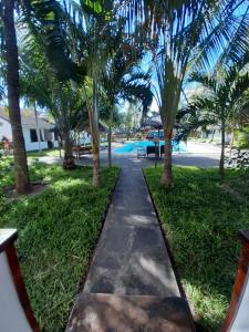 a walkway through a park with palm trees at Eden House Cottages in Malindi