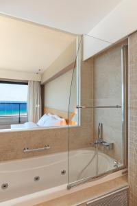 a bathroom with a shower and a bed and a tub at Cactus Hotel in Rhodes Town