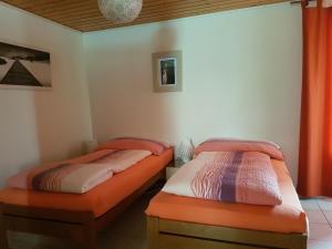 two twin beds in a room with red curtains at BNB Tuileries in Grandson