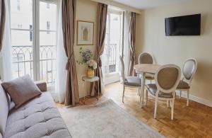 a living room with a couch and a table with chairs at Apartments Du Louvre St Honoré in Paris
