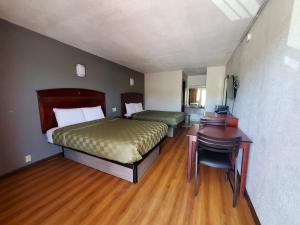 a bedroom with two beds and a desk and a desk at Welcome Inn in Dallas