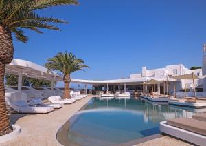 a swimming pool with lounge chairs and palm trees at Andronikos Hotel in Mýkonos City