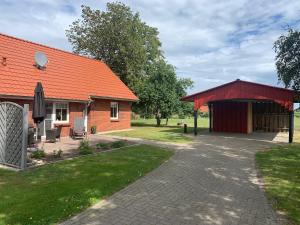een huis met een oranje dak en een patio bij Weideblick in Upgant-Schott
