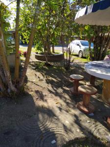 Pousada Bom Clima em Gravatá - Servimos cestas de Café da Manhã في غرافاتا: طاولة نزهة ووجود كرسيين في الحديقة