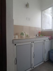 a kitchen with white cabinets and a sink and a window at Ameesha Lodge Apartment in Nugegoda