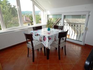a dining room with a table and chairs and windows at Studio apartmani Sofija in Vrdnik