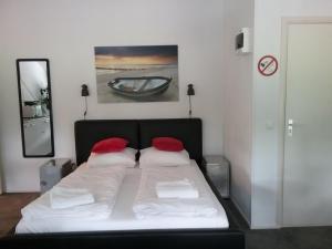 een slaapkamer met een bed met 2 rode kussens bij De Strandgaper in Zevenhuizen