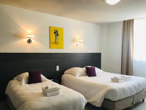 um quarto de hotel com duas camas com toalhas em HÔTEL LE CHAPON FIN em Moissac