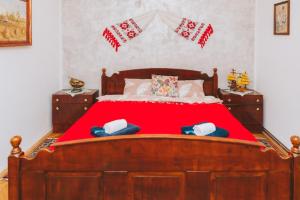 Un dormitorio con una gran cama de madera con sábanas rojas. en Casa Vinco Vici, en Turda