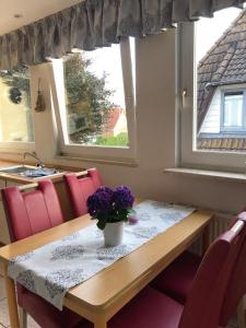 uma mesa de jantar com um vaso de flores roxas em Haus Trossenstek V em Büsum