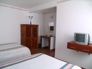 a bedroom with two beds and a tv on a dresser at Posada de San Agustin in Pátzcuaro