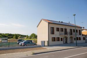 a white building with cars parked in a parking lot at Venezia Fly Apartments in Tessera